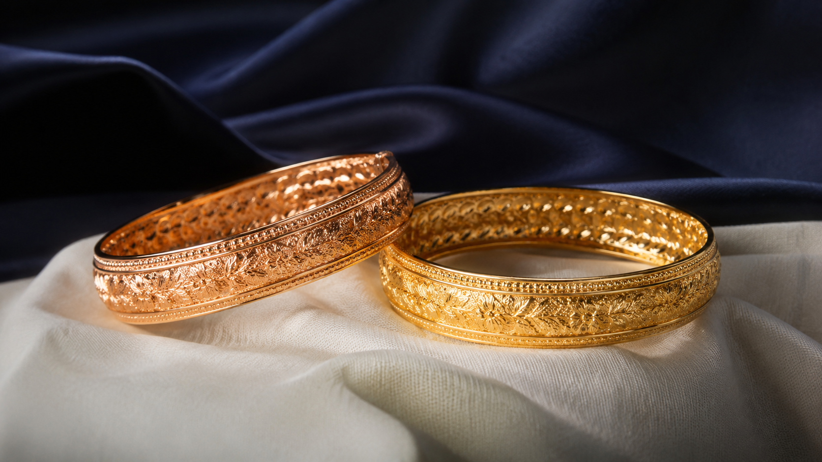 Two gold bangles side by side on white linen, one slightly warmer in tone than the other